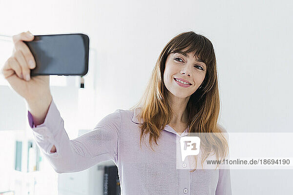 Smiling woman taking selfie through smart phone