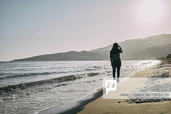 Frau geht am Strand in Ufernähe spazieren