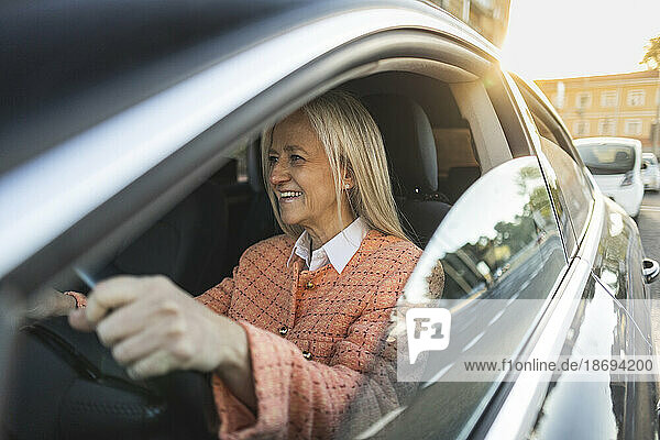 Smiling mature woman driving car