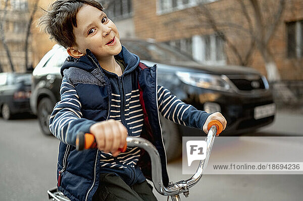 Lächelnder Junge fährt Fahrrad auf der Straße