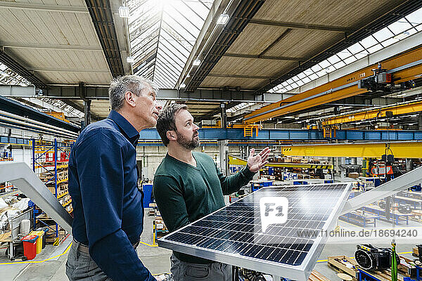 Businessmen with solar panel having discussion in factory