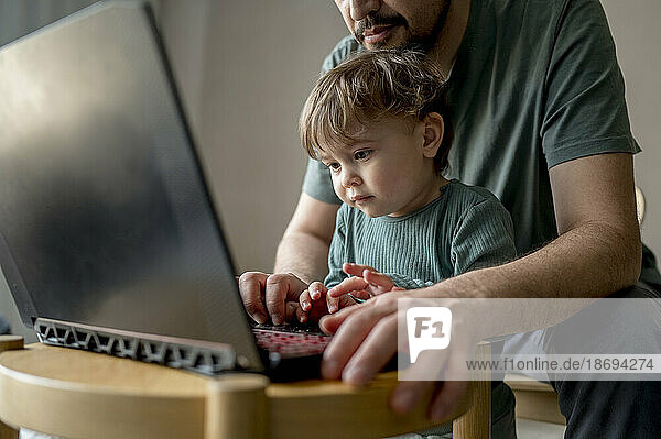 Vater und Sohn benutzen Laptop zu Hause
