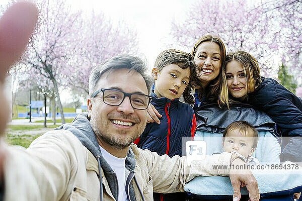 Father taking selfie with family at park