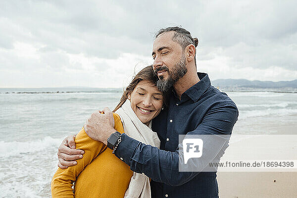 Smiling mature man hugging woman at beach