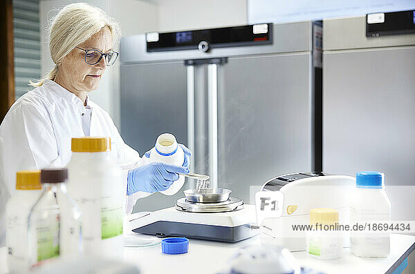 Scientist measuring chemical on weight scale in laboratory