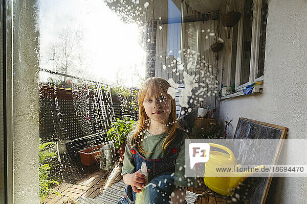 Redhead girl cleaning window glass