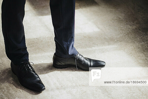 Beine eines Geschäftsmannes mit schwarzen formellen Schuhen  der in der Fabrik steht