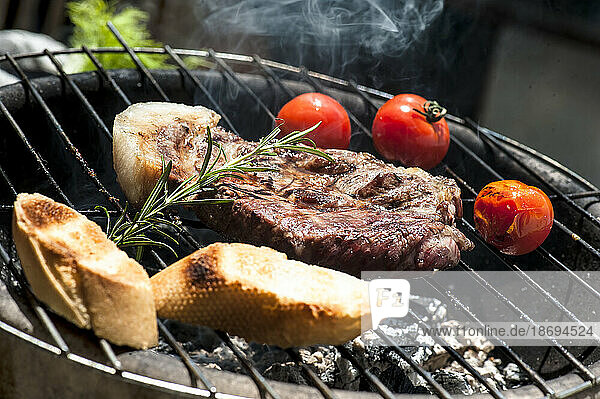 Meat  tomatoes and baguette slices cooking on barbecue grill