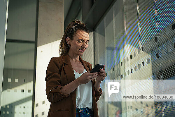 Businesswoman surfing net through smart phone at office
