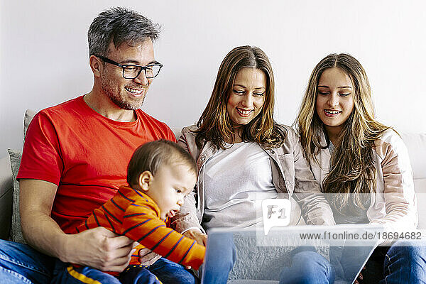 Smiling family watching laptop together sitting at home