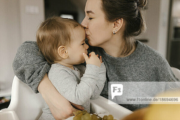 Mother kissing son on forehead at home
