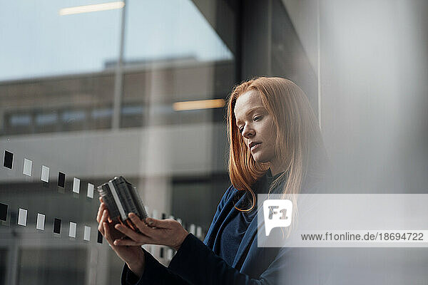 Redhead businesswoman analyzing machine part at window