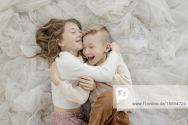 Brother and sister lying on tulle net