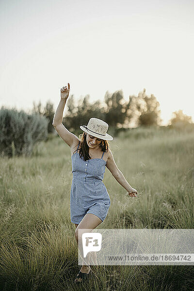 Cheerful woman running on meadow at sunset