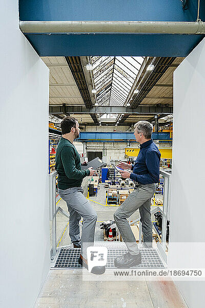 Businessman discussing with colleague in factory