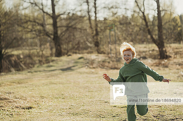 Carefree girl running in forest on sunny day