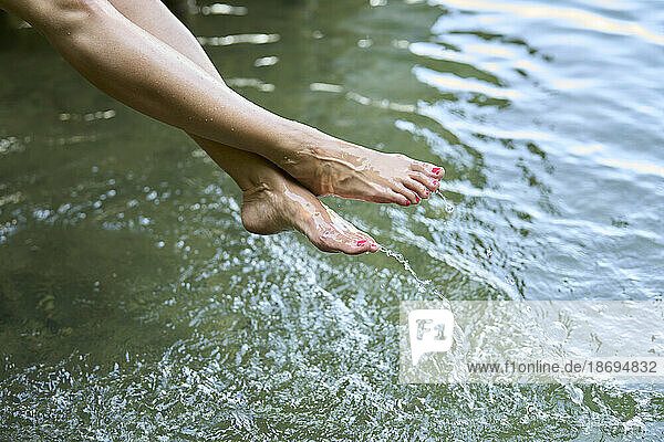 Woman with barefoot splashing water in lake