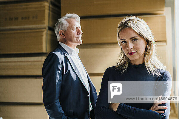 Confident blond businesswoman with senior businessman in background