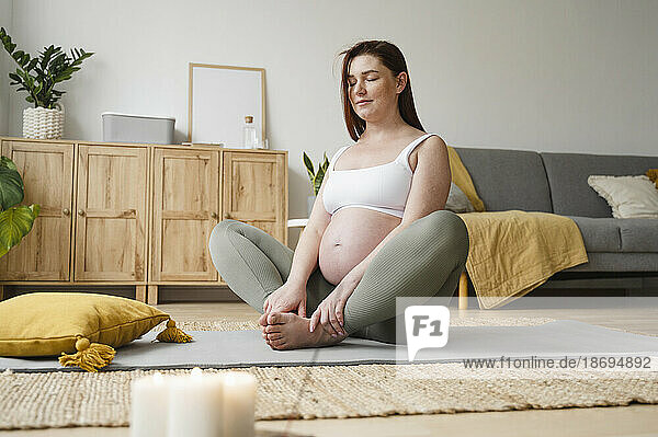 Pregnant woman doing meditation with eyes closed at home