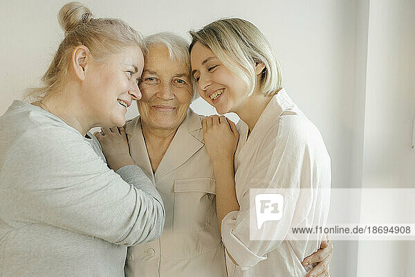 Women embracing grandmother at home