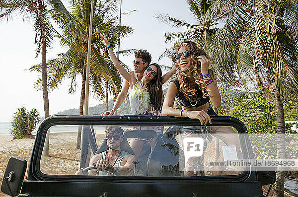 Happy friends enjoying off-road vehicle trip at beach