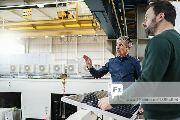 Businessman and manager discussing over solar panel at factory