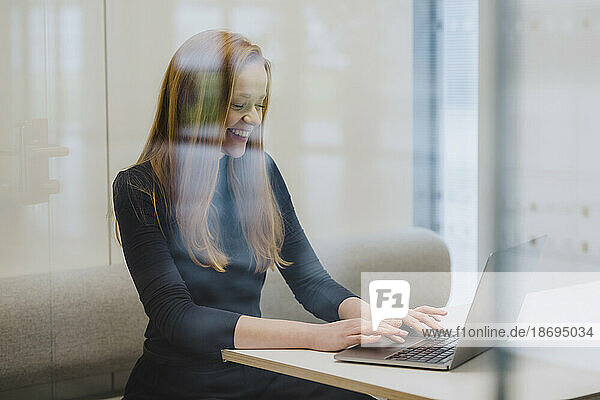 Smiling businesswoman working in office cubicle