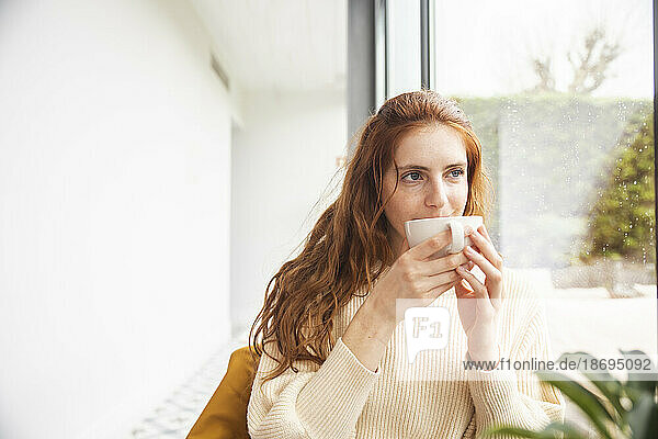 Redhead woman drinking coffee in hotel