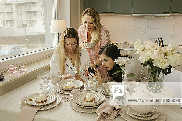 Freunde fotografieren Kuchen per Smartphone in der heimischen Küche