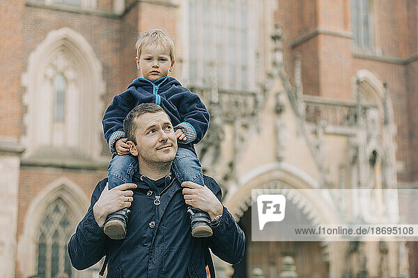 Father carrying son on shoulders in front of cathedral