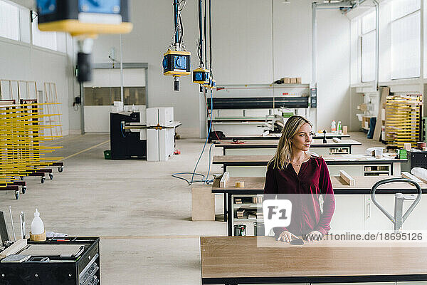 Businesswoman standing near workbench at factory