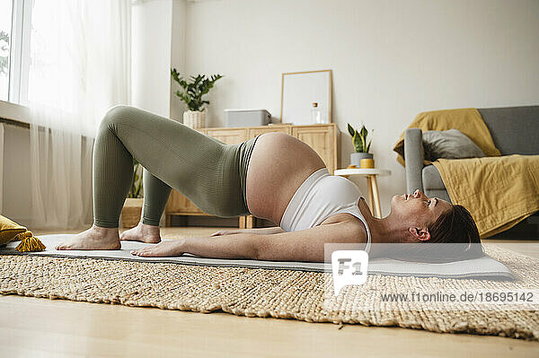 Pregnant woman doing prenatal yoga on exercise mat at home