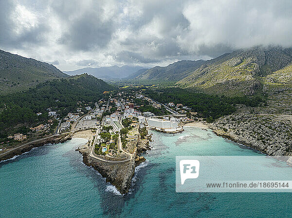 Spain  Balearic Islands  Cala Sant Vicenc  Aerial view of coastal town with mountains in background