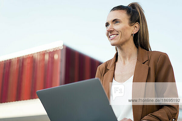 Nachdenkliche junge Geschäftsfrau mit Laptop