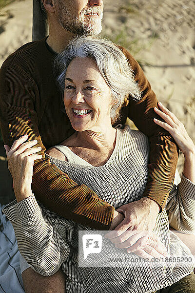 Cheerful woman embraced by man at beach