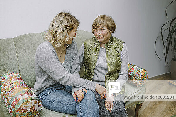 Lächelnde Großmutter sitzt mit Enkelin auf dem Sofa