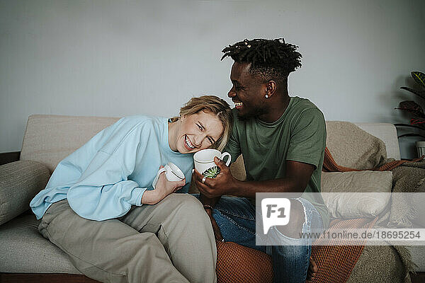 Happy woman laughing with man holding coffee mug at home