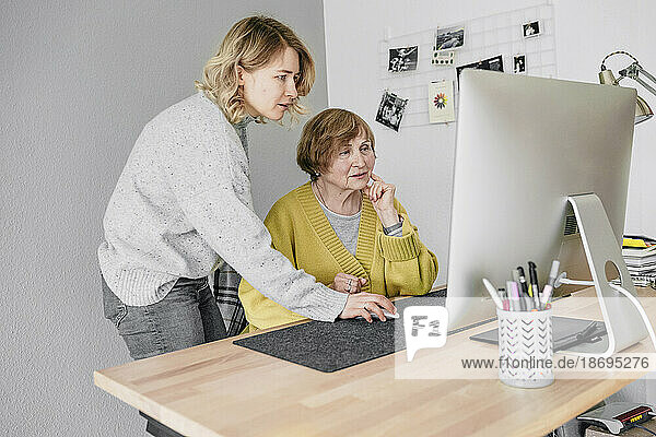 Grandmother and granddaughter using computer at home