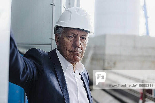 Senior businessman wearing hard hat in factory