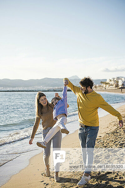 Father and mother picking up daughter at beach