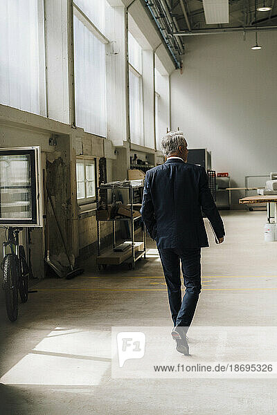 Senior businessman walking in factory