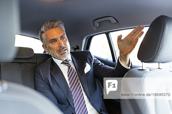 Reifer Geschäftsmann gestikuliert im Auto sitzend