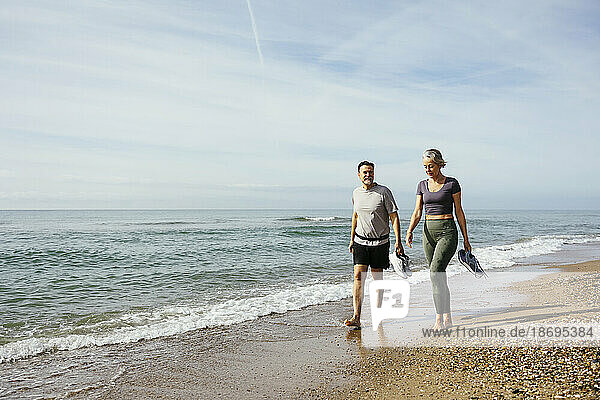 Mature couple walking on sand near sea at beach