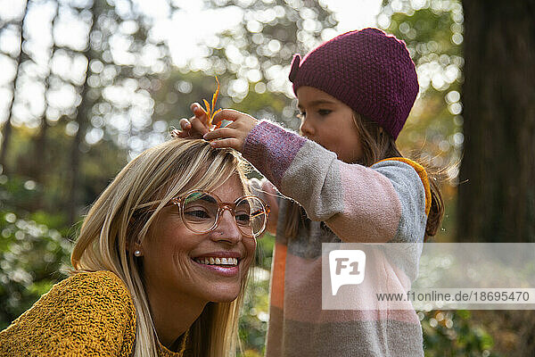 Daughter putting leaf in mother's hair