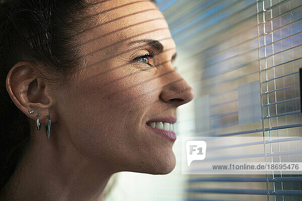 Smiling businesswoman wearing earrings looking out of window at office