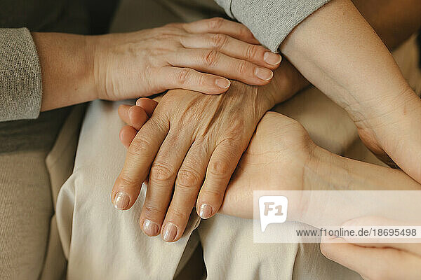 Elderly woman stacking hands with family at home