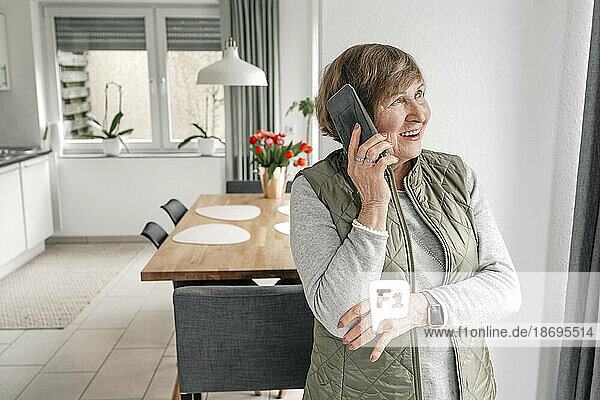 Ältere Frau telefoniert zu Hause mit dem Smartphone