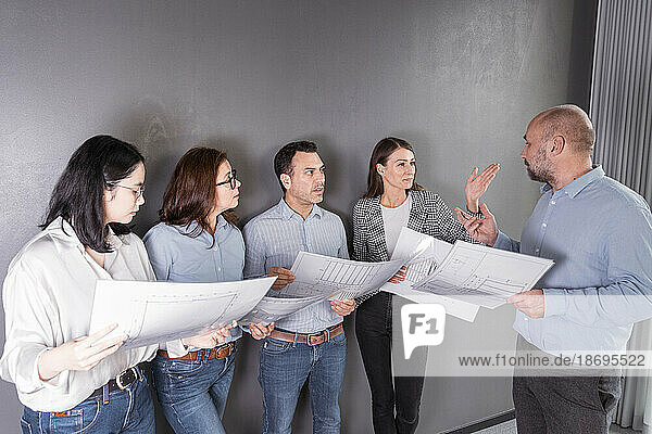 Business people standing at a wall working on an architectural project