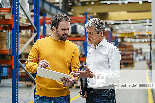 Businessman with colleague discussing in factory