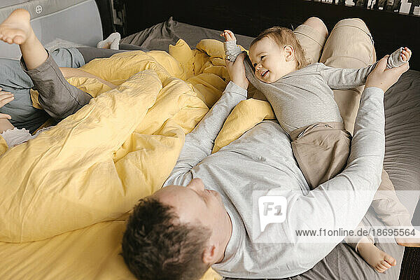 Father having fun with son on bed at home